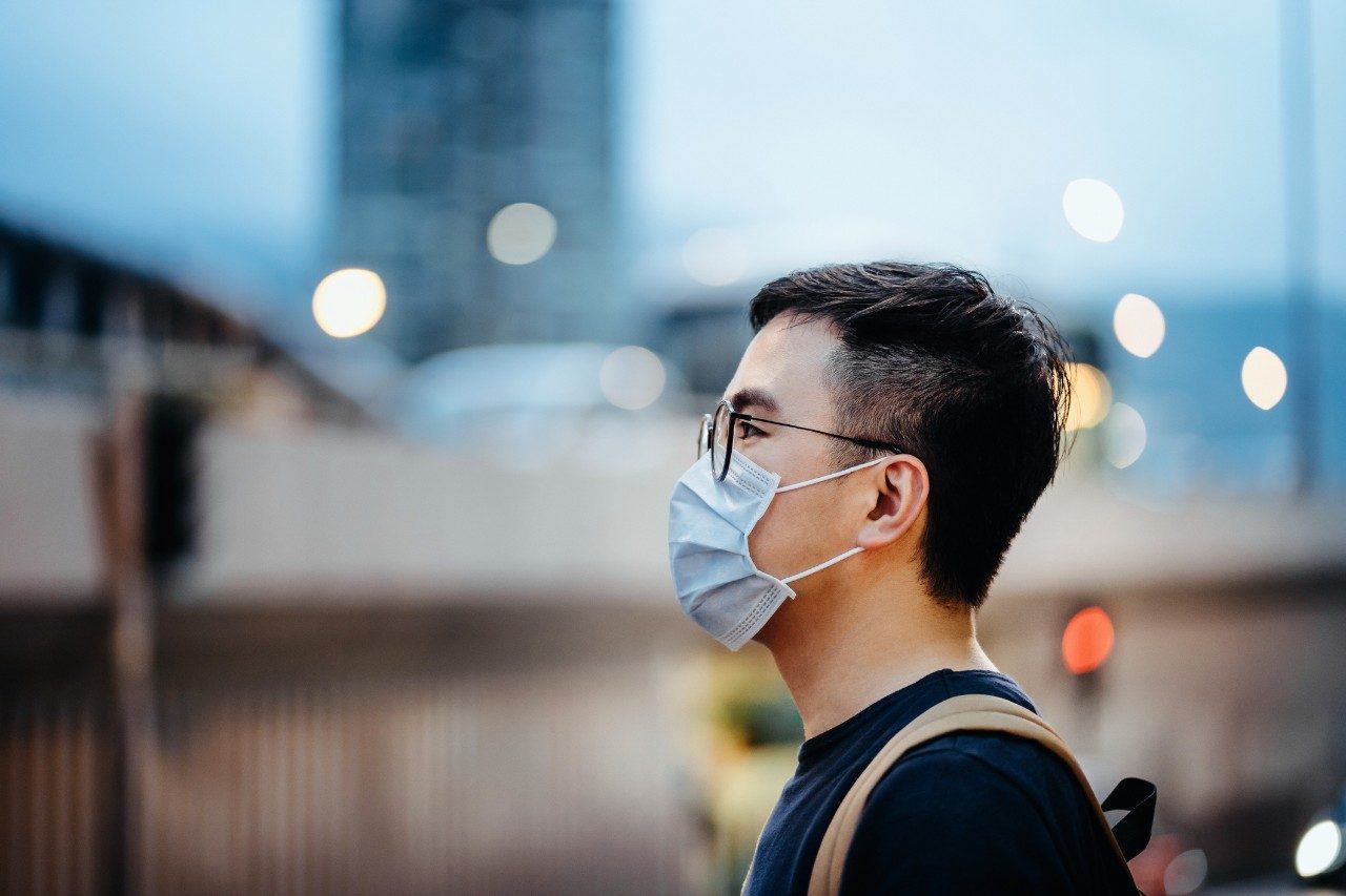 戴口罩的年轻亚裔男子的肖像，保护和防止病毒在城市传播