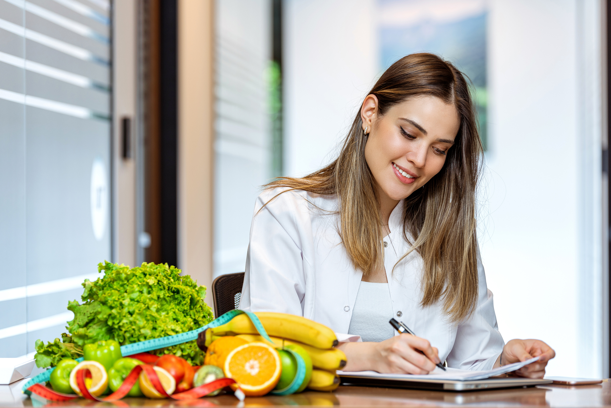 营养师在她的办公室里微笑着展示健康的蔬菜和水果。