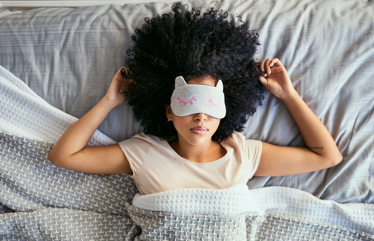 一位年轻女性在床上戴着口罩睡觉的照片