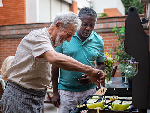 两位老年男性正在为朋友们的素食晚餐准备烧烤。