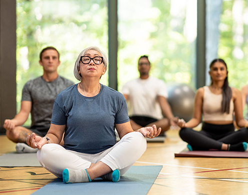 一群多元化的成年人在健身房的瑜伽垫上冥想。